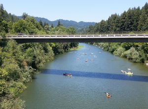 people floating down river underneath bridge