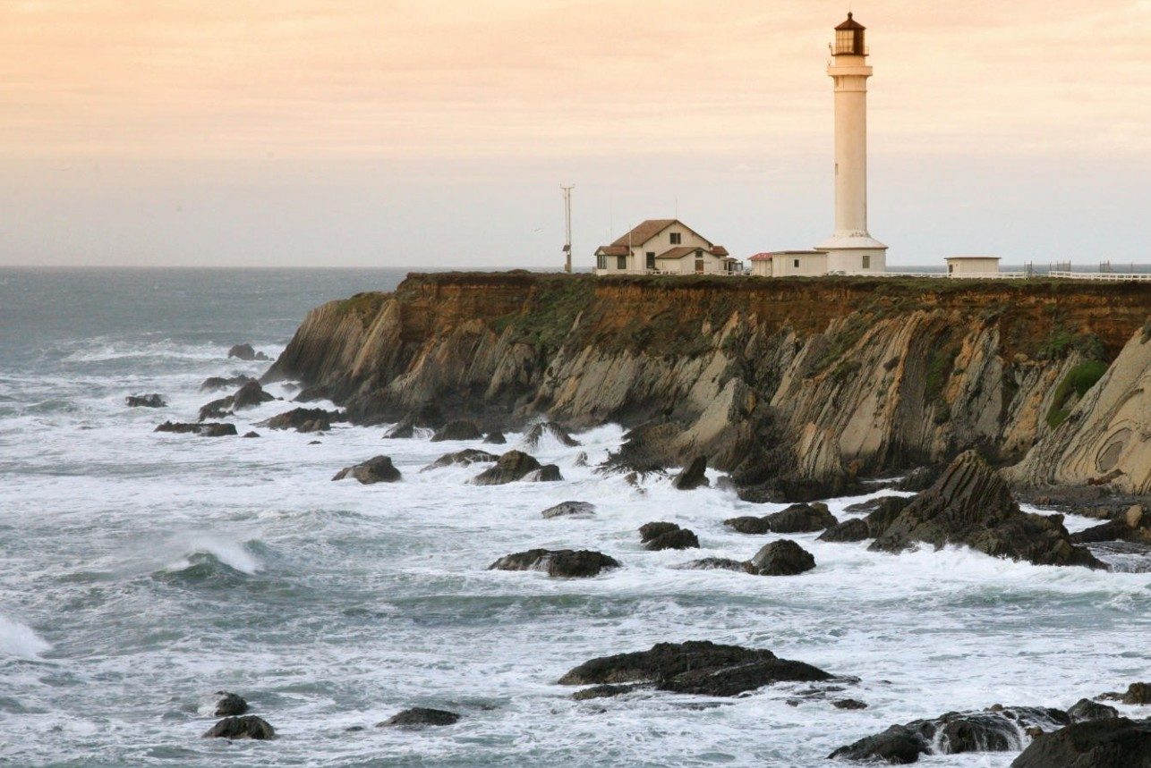 lighthouse sits ontop of cliffs overlooking the ocean