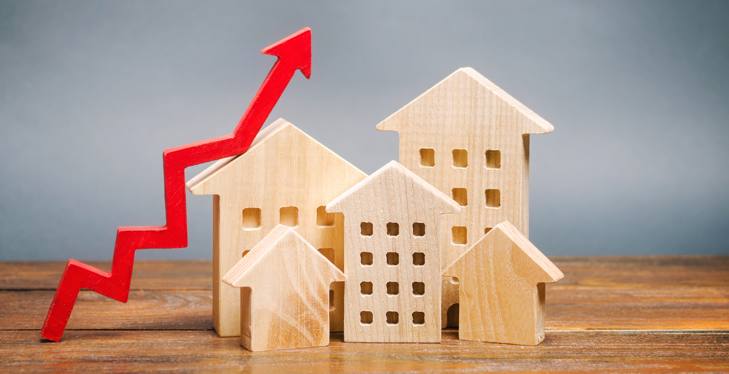 Real estate market trends concept; Miniature wooden houses and red arrow up.