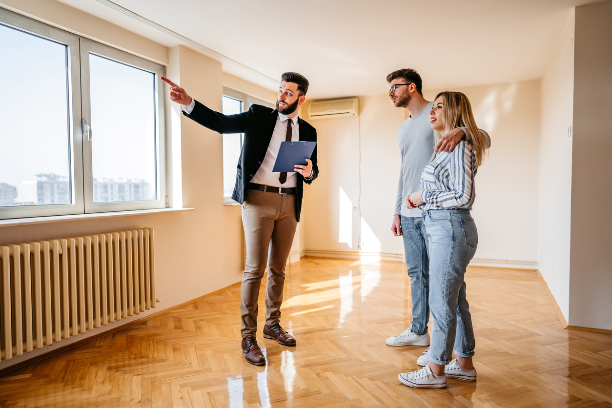 Real estate agent showing an apartment for sale to a young couple during an open house
