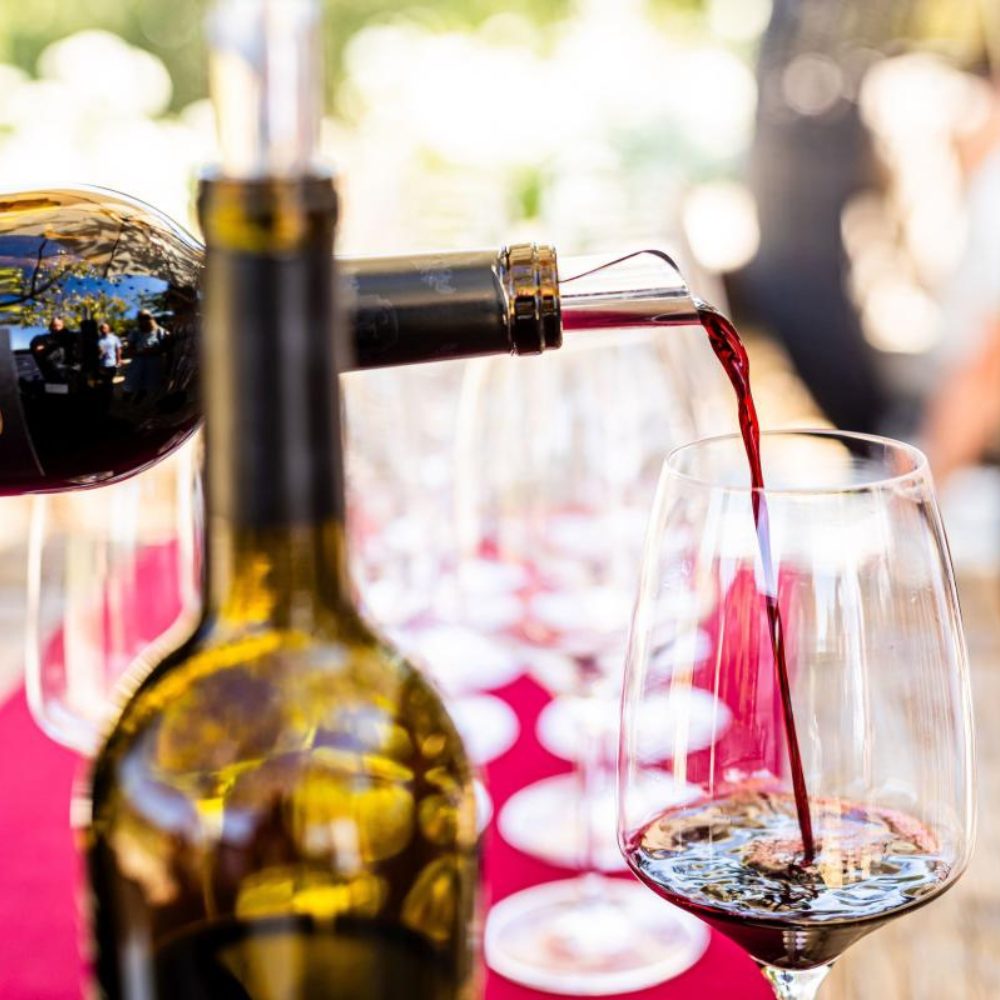 Red wine is poured into an empty wine glass